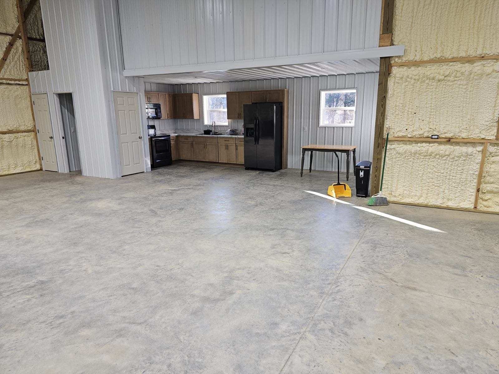 Empty warehouse with concrete floor, open workspace, and table with cleaning supplies near the back wall