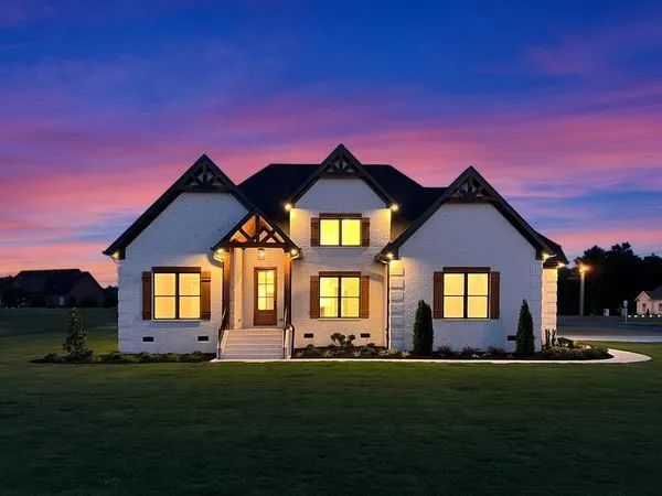 Modern suburban house with warm lights at dusk under a purple and pink sky