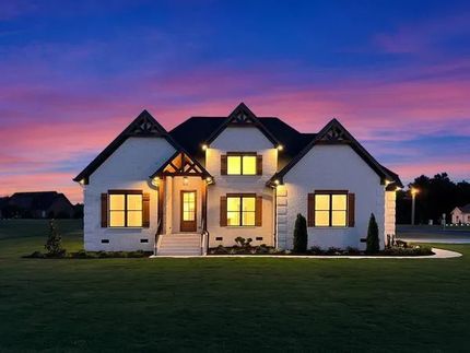Modern suburban house with warm lights glowing at dusk under a purple sunset sky