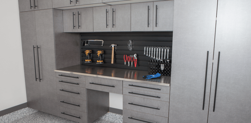 Gray garage cabinets with workbench, tools on pegboard, and storage drawers.