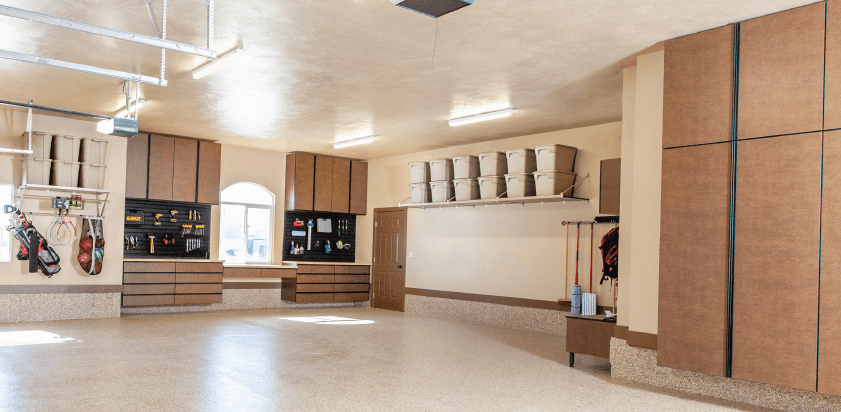 Spacious garage with cabinets, workbenches, and open space. Neutral colors, overhead lighting, organized storage.