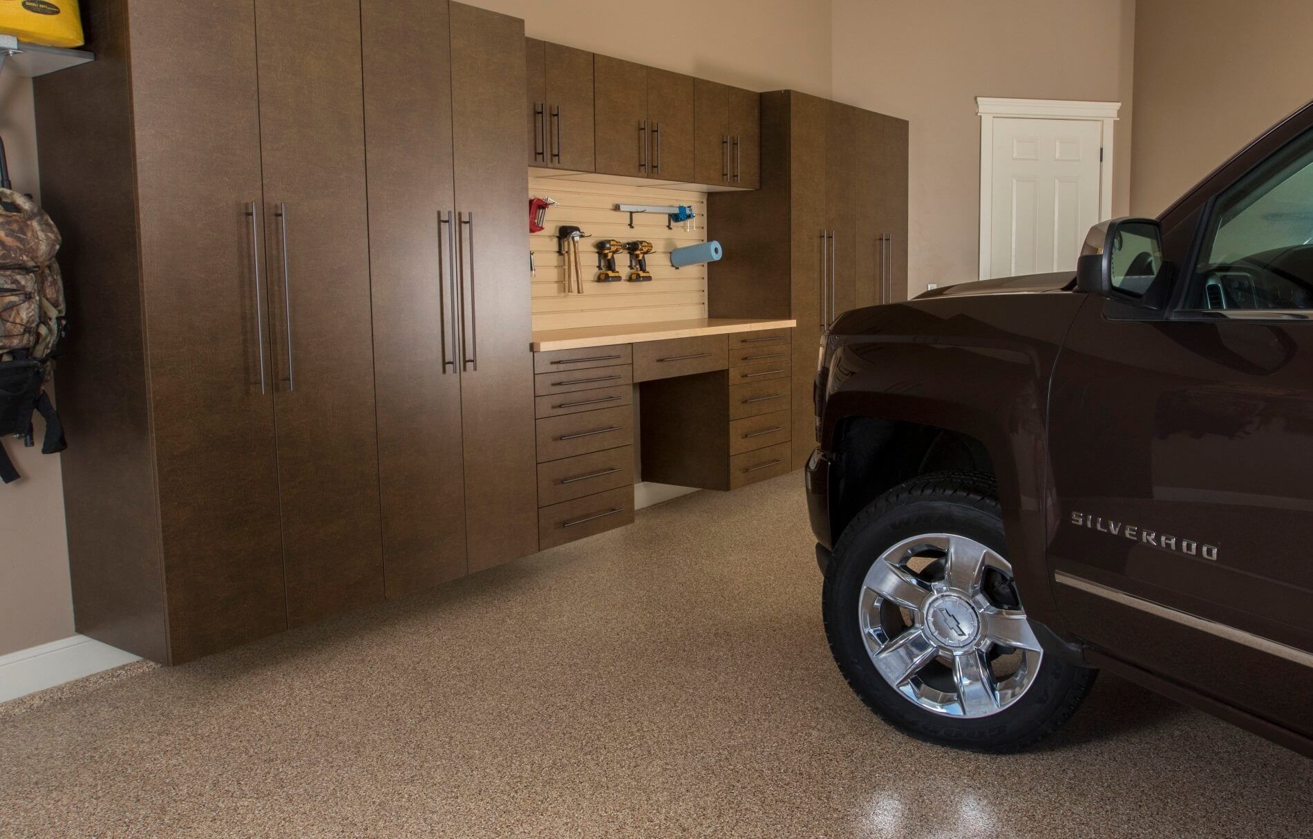 Garage interior with brown cabinets, workbench, and brown truck.