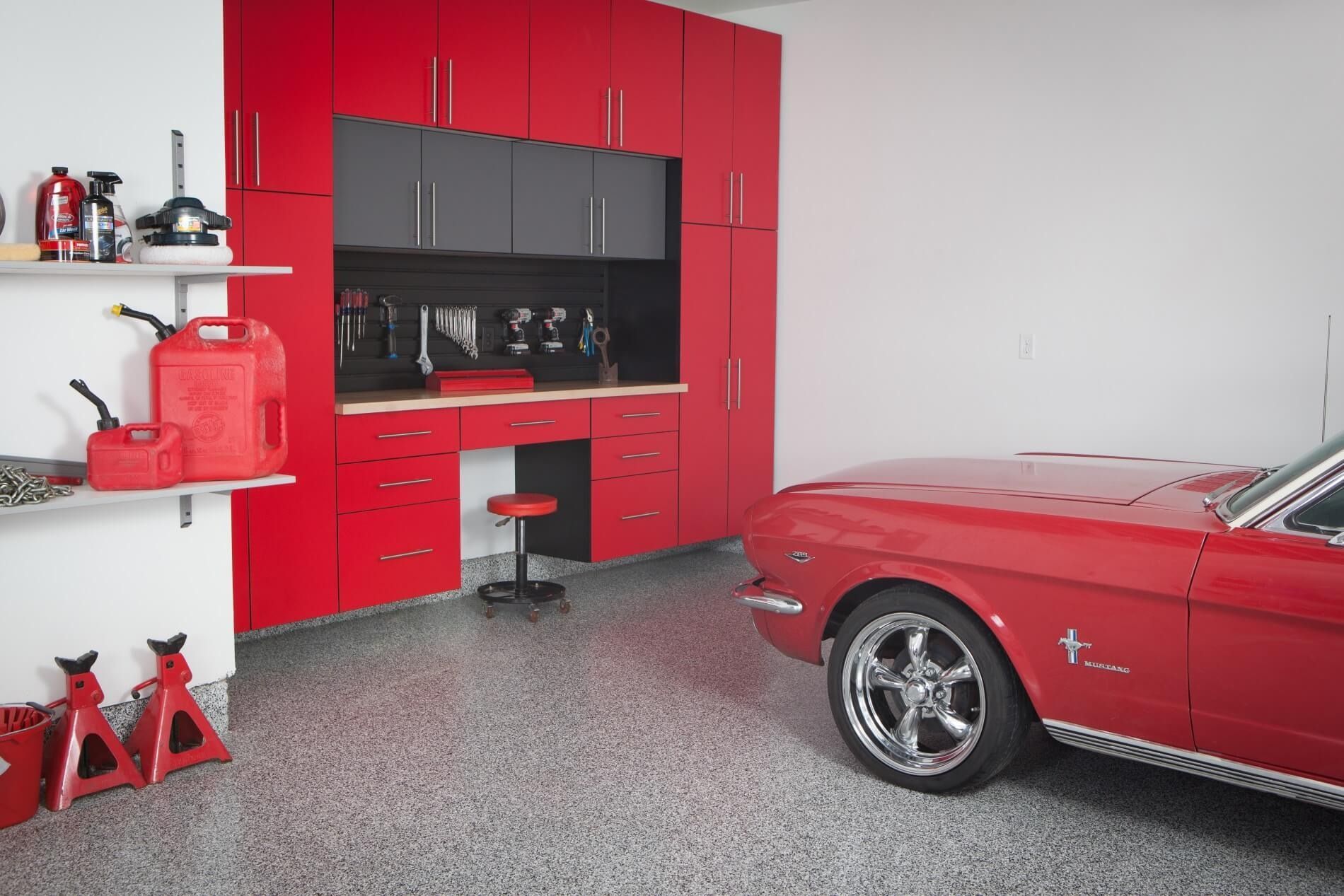 Red garage with a classic red car, cabinets, and a workbench.