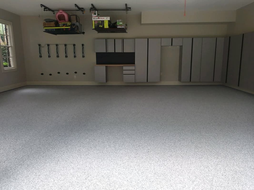 Gray epoxy garage floor with storage cabinets and tools.