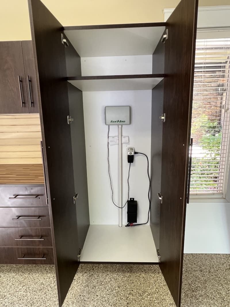 Open, dark wooden cabinet with white interior holding electronic equipment against a white wall.