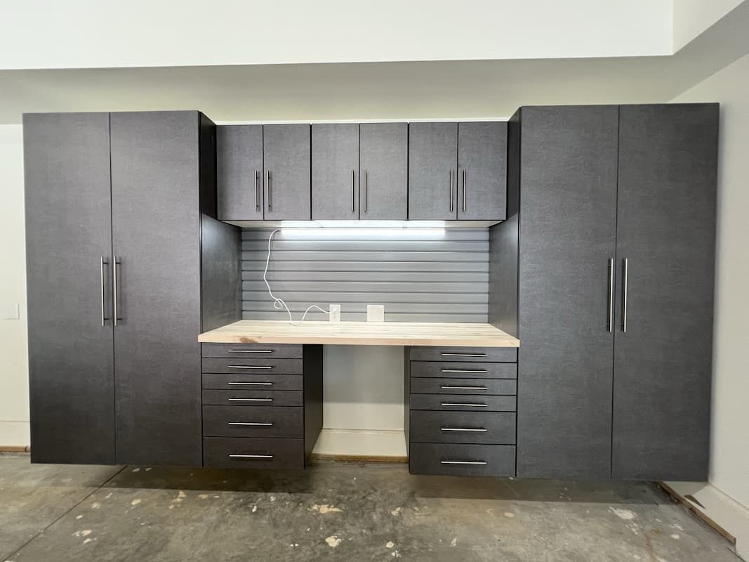 Dark gray cabinets with workbench and drawers in a garage setting.