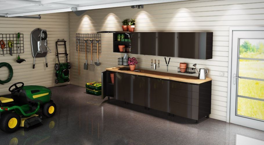 Garage interior with dark cabinets, a work surface, and lawn equipment.