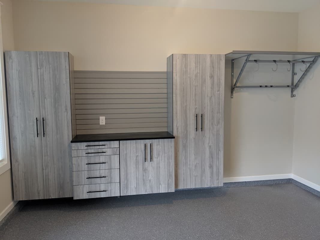 Garage organization system: light gray cabinets, drawers, slatted wall, and a folding shelf.