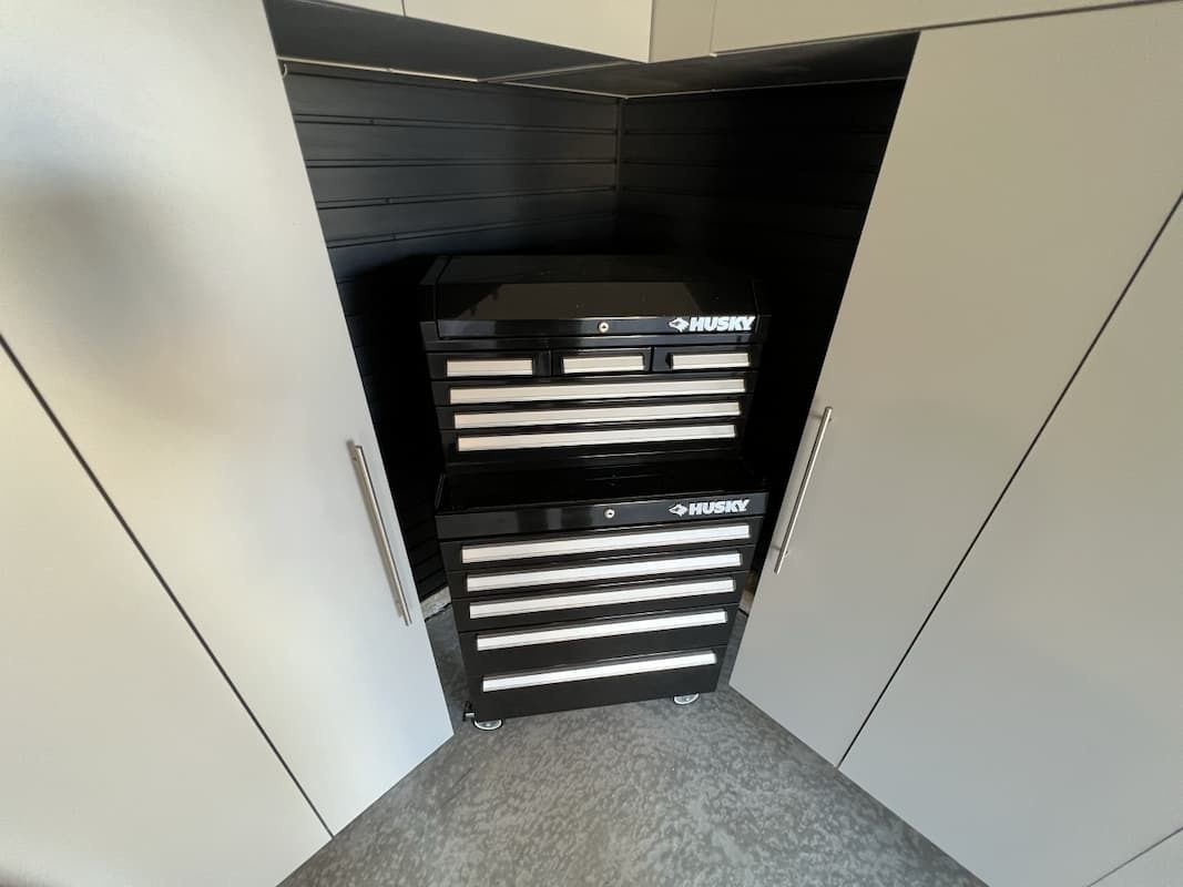Two black Husky tool chests inside a gray cabinet.