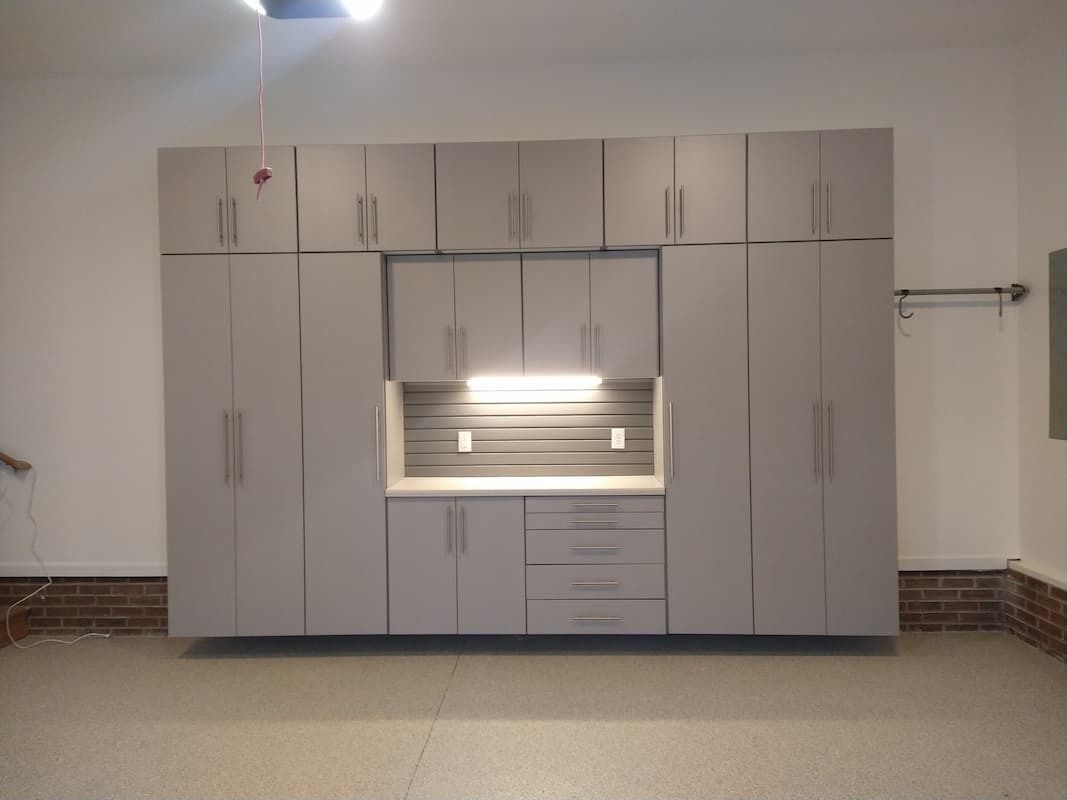 Gray garage cabinets against a white wall with a strip of lights.