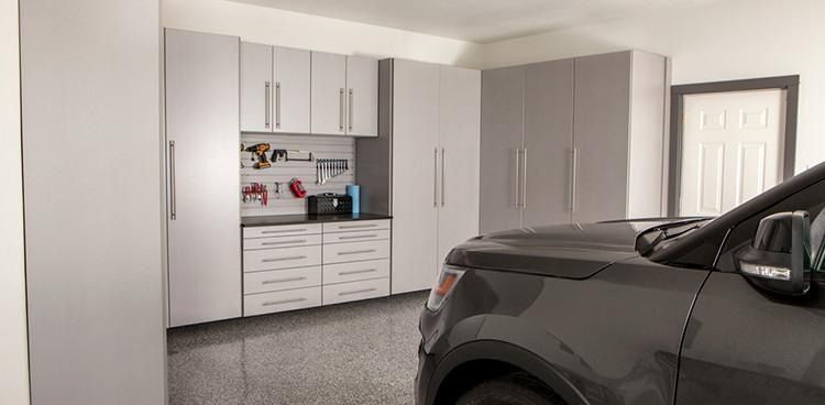 Garage interior with gray cabinets, a black counter, and a dark SUV.