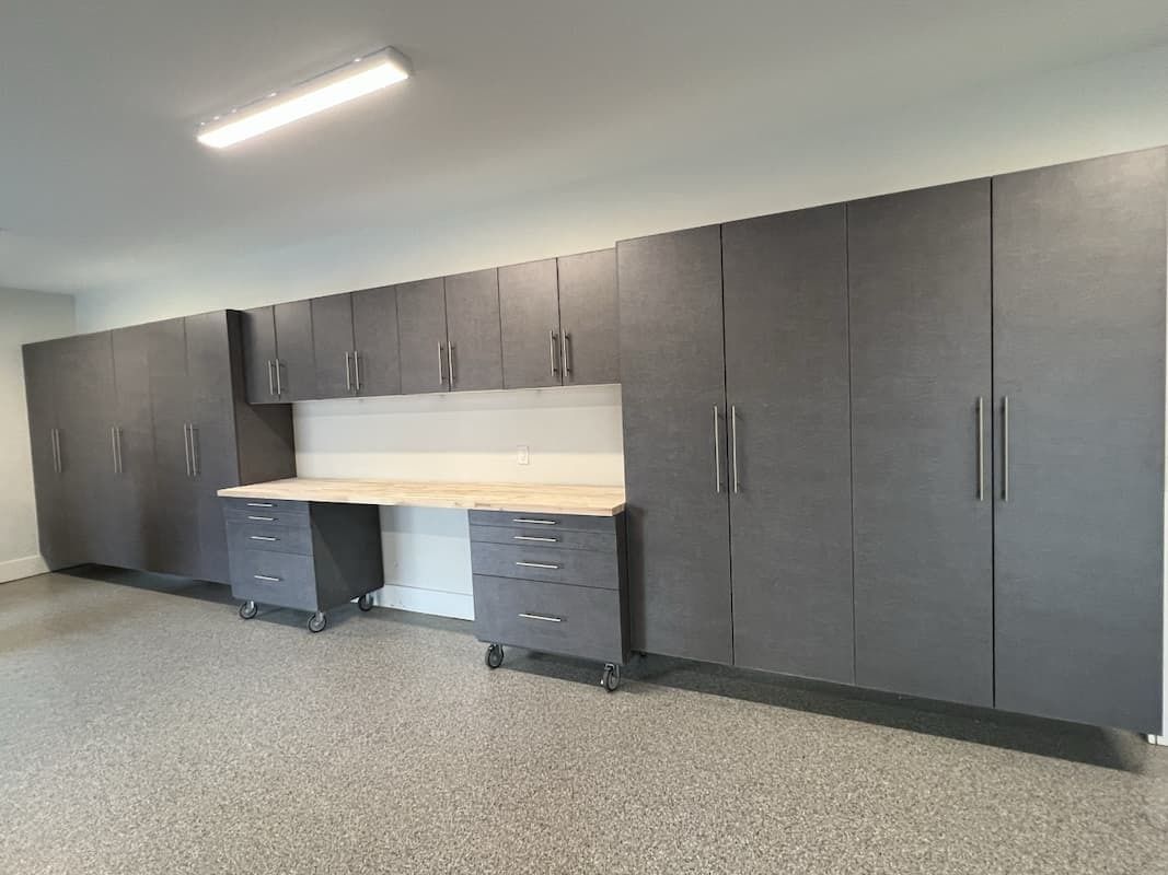 Gray garage cabinets and workbench against a white wall in a garage.