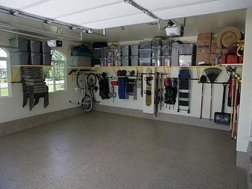 Clean, organized garage interior with storage shelves, bins, and wall-mounted tools and equipment.