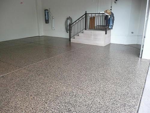 Garage interior with a polished, speckled concrete floor and a staircase in the back.