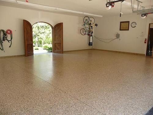 Empty garage with a polished concrete floor and open wooden doors.