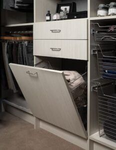 Closet with clothes and drawers, including a pull-out laundry hamper and wire shelves.