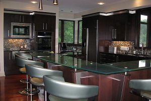 Modern kitchen with dark cabinetry, glass countertop island, and bar stools.
