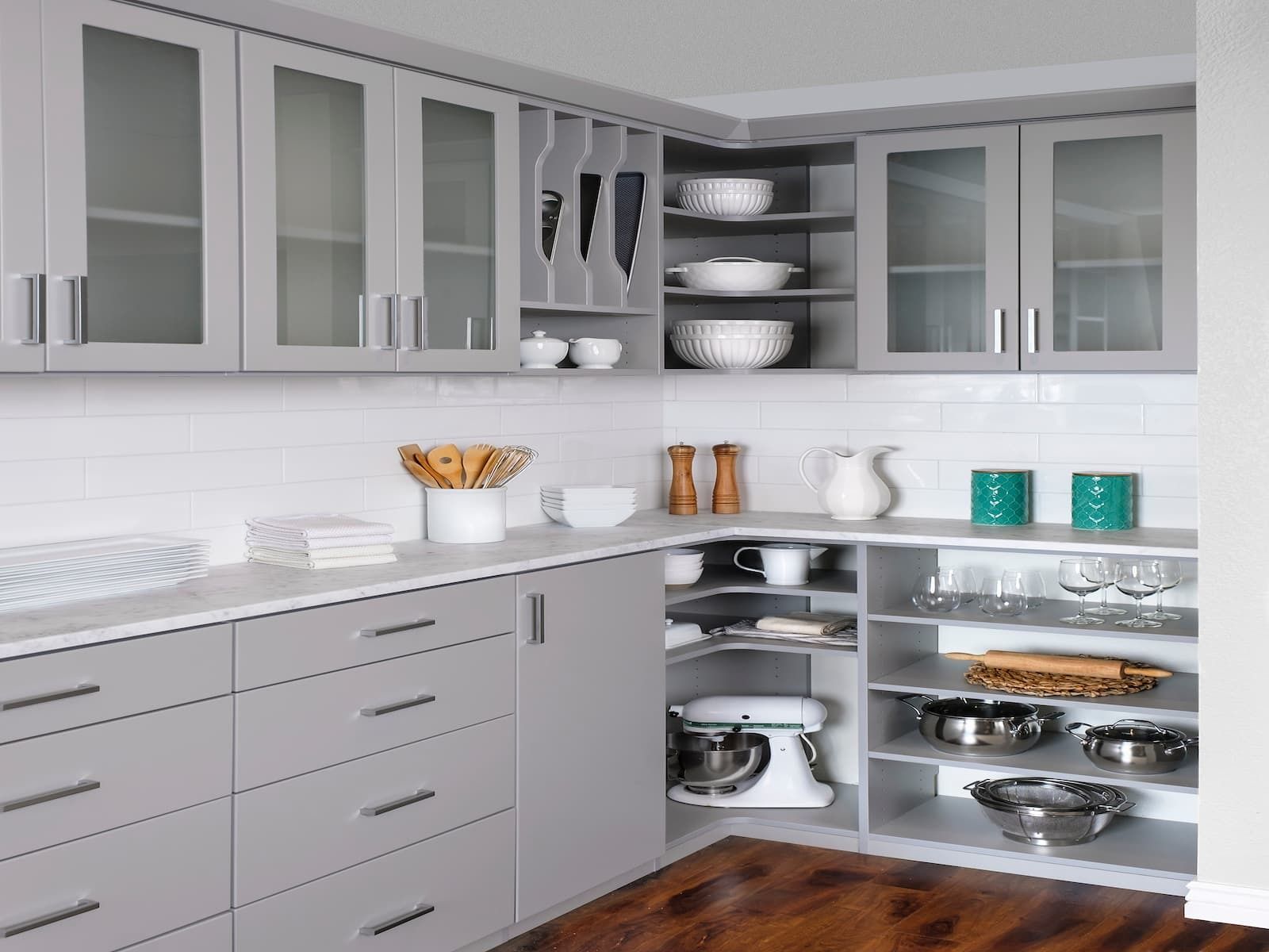 Gray kitchen with corner cabinets, white countertop, and wooden floor.