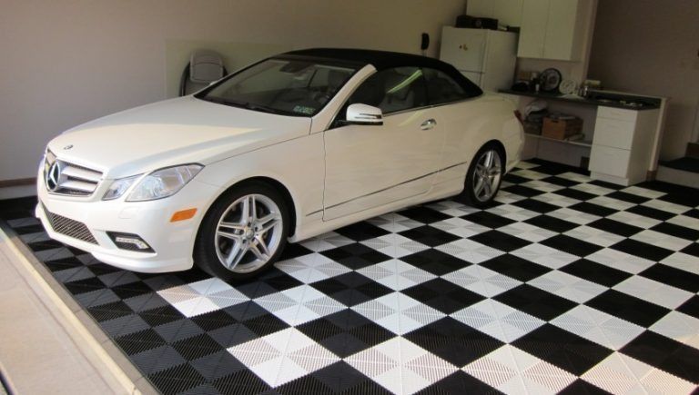 White Mercedes convertible parked on a black and white checkered garage floor.