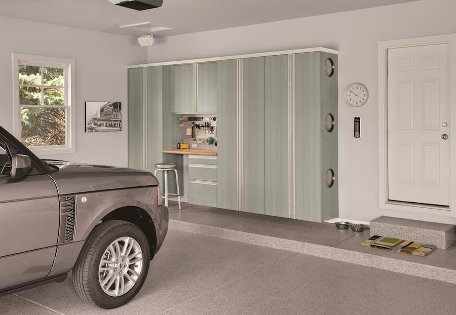 Garage interior with grey SUV, light green cabinets, and a white door.