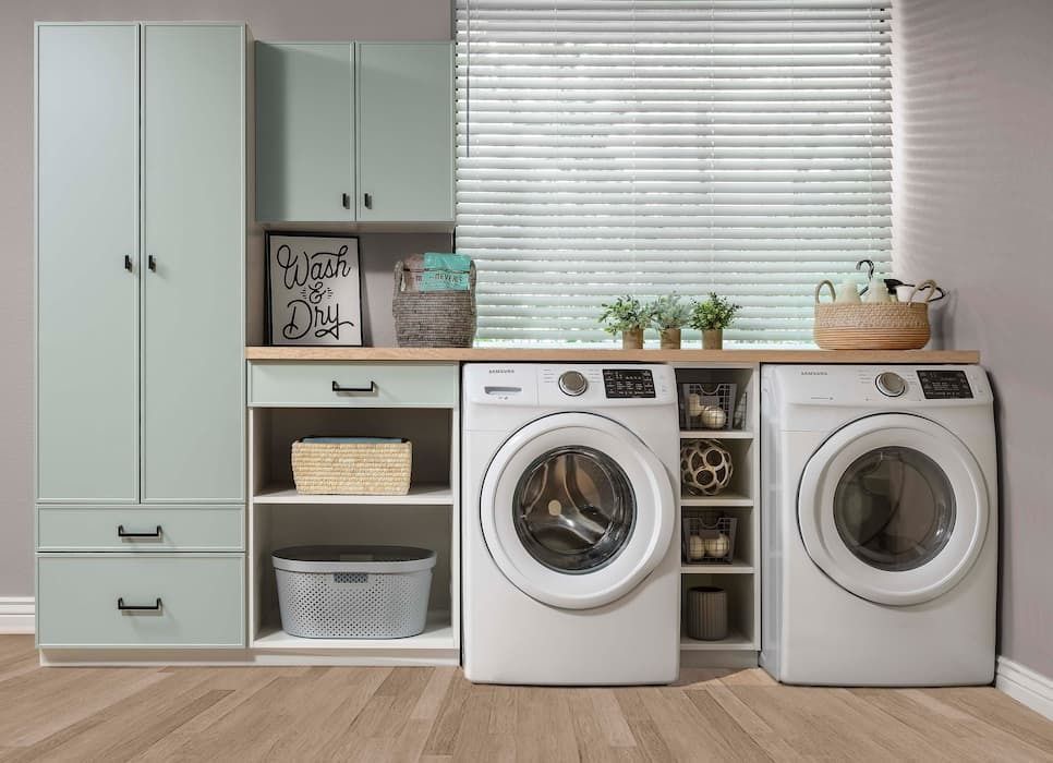 Laundry room with washer, dryer, cabinets, and baskets in a light green and wood-tone color scheme.