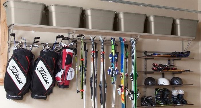 Garage storage system holding golf clubs, skis, and bins.