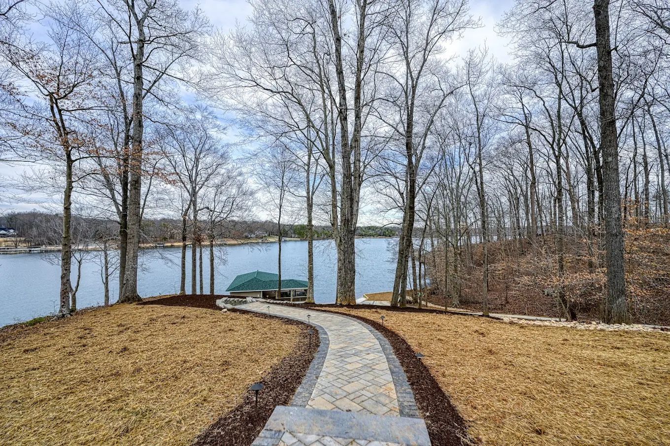 A path leading to a lake surrounded by trees on a cloudy day.