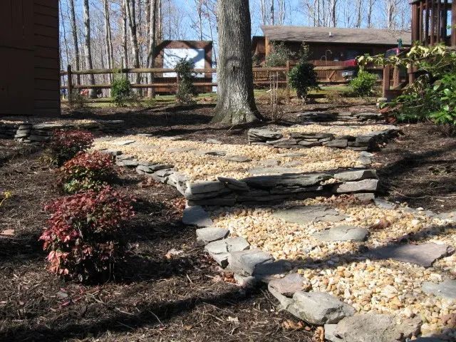 A stone walkway leading to a house in the woods