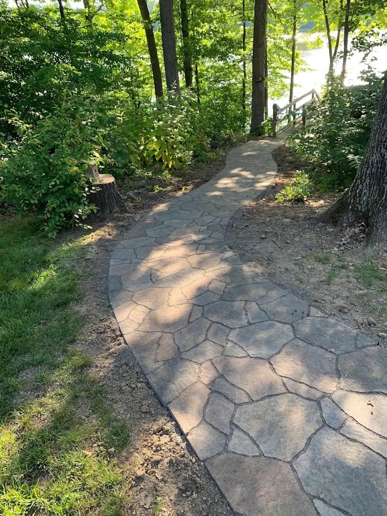 A stone walkway leading to a lake in the woods.