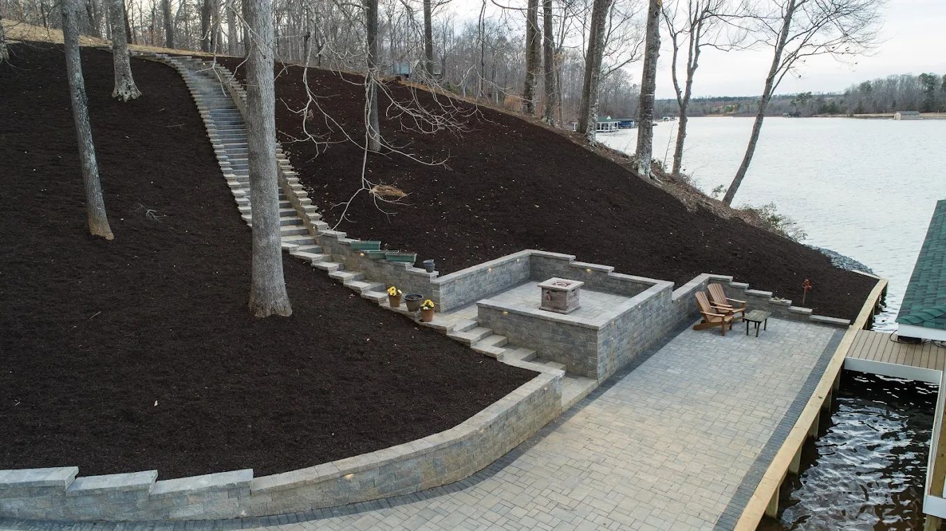 A patio with a fire pit and stairs next to a lake