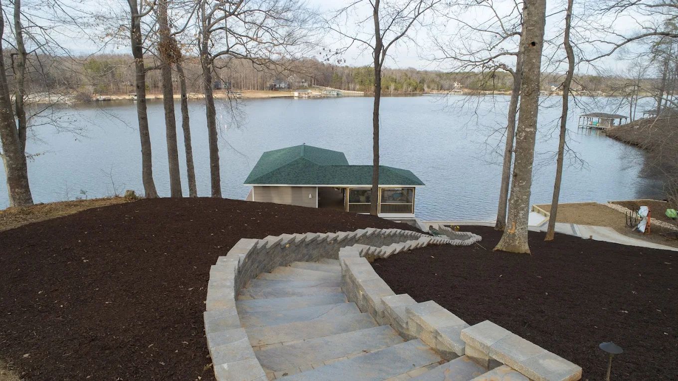 Stairs leading up to a lake with a house in the background