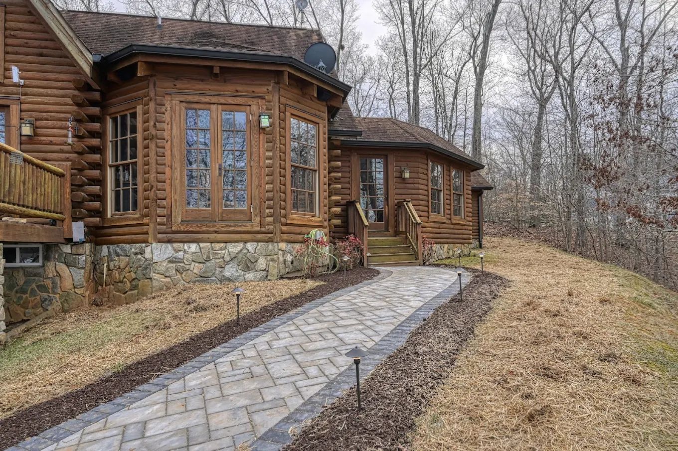 A log cabin with a stone walkway leading to it in the woods.