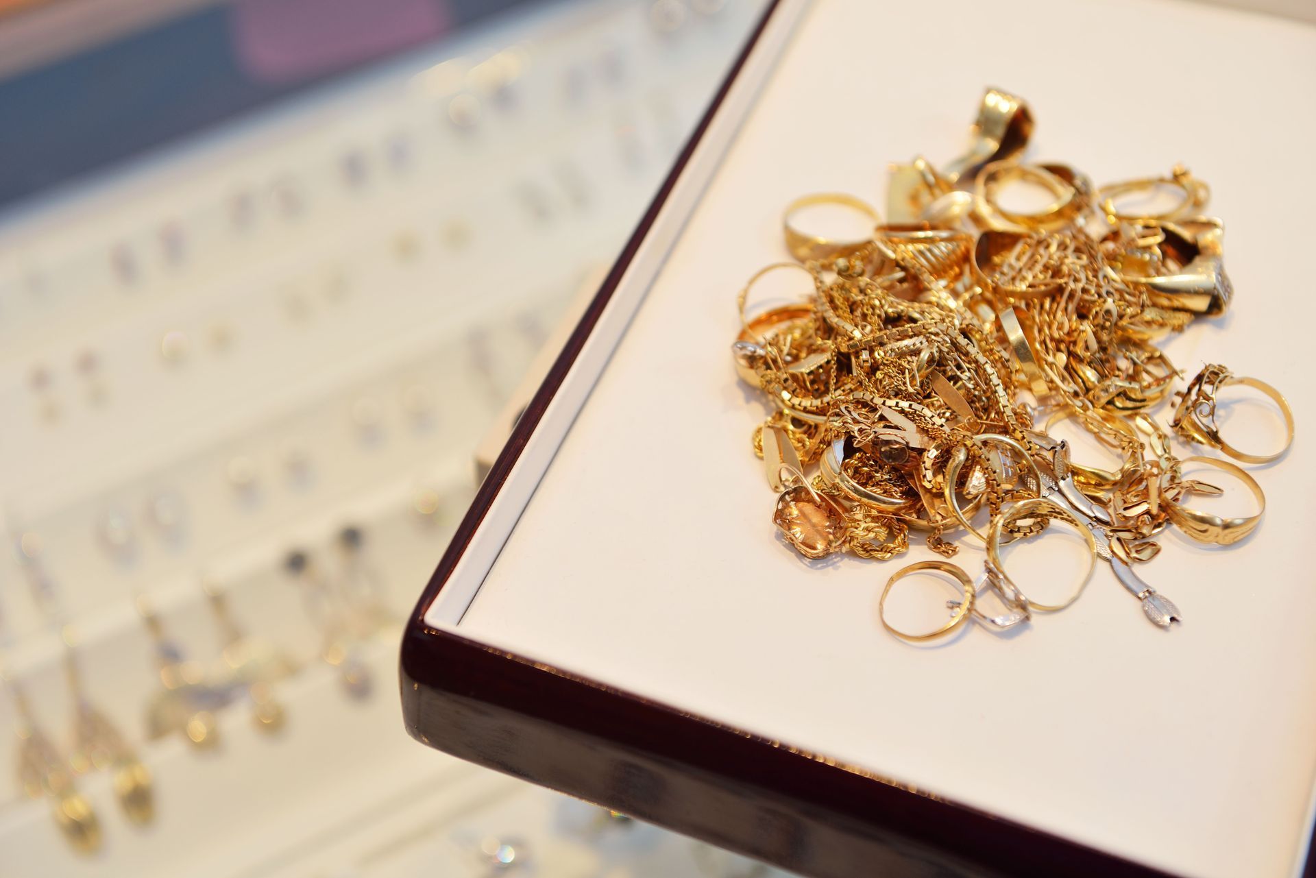 Gold jewelry laid out on a white tray beside a display case with rings.