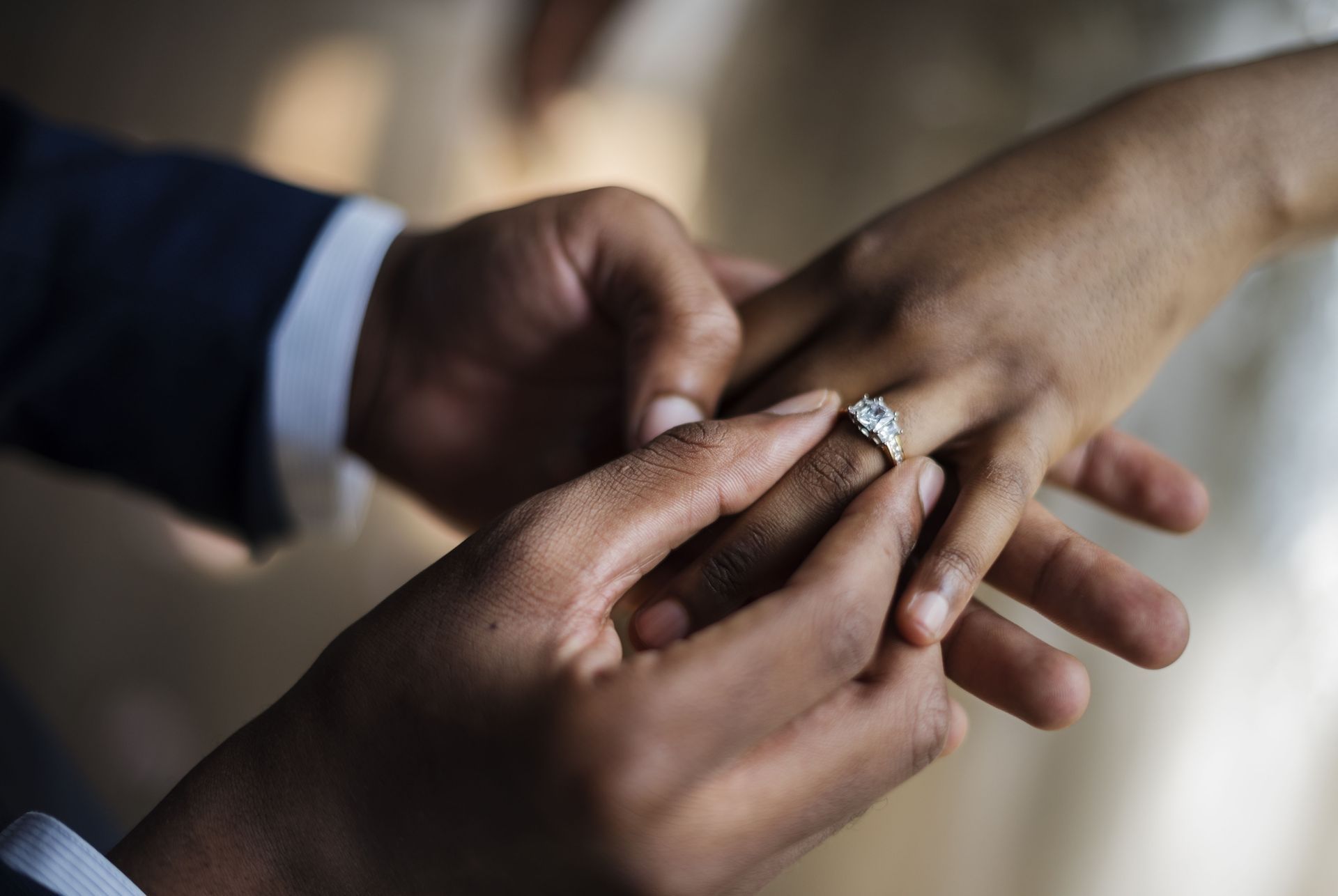 Hands placing a ring on another person's finger during a wedding ceremony