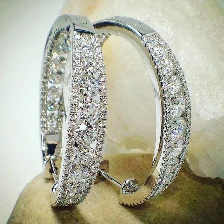 Silver crystal-studded hoop earrings displayed on a pale background
