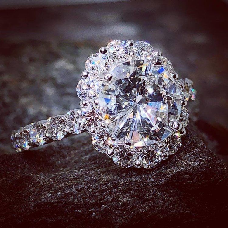 Diamond engagement ring with halo setting on a dark textured surface