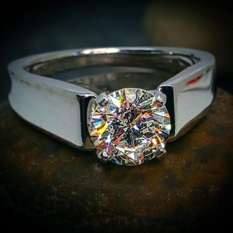 Diamond solitaire ring on a silver band, close-up against a dark background