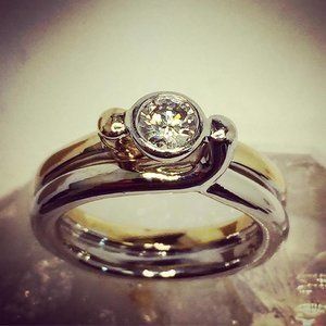 Two silver rings with a round diamond setting on a soft, blurred background