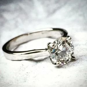 Silver ring with a round-cut diamond solitaire on a soft gray background