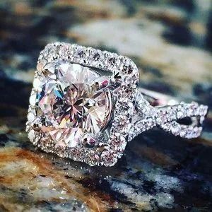 Close-up of a diamond ring with a large round center stone and halo setting on a marbled surface