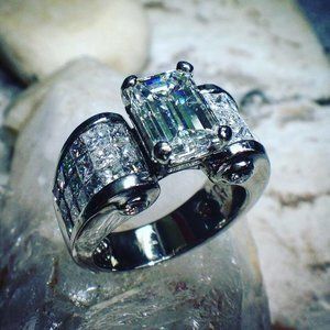 Silver diamond ring with a large rectangular center stone and pavé band on a white surface