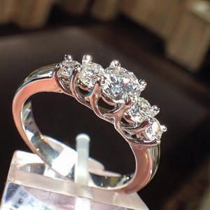 Silver ring with five sparkling diamonds on a display stand