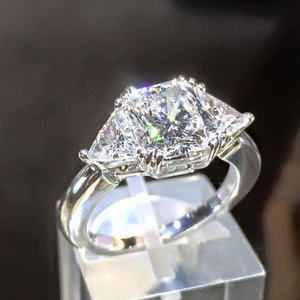 Diamond ring on a clear display stand, with a sparkling faceted gemstone.
