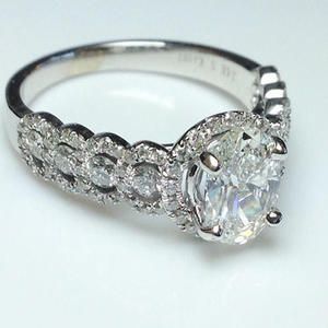 Silver ring with a large oval diamond and a pavé band on a white background