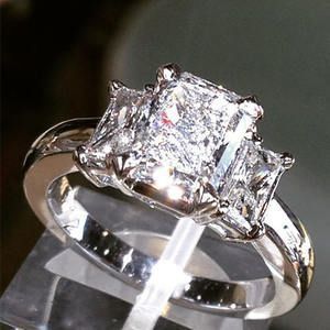 Silver ring with a square-cut diamond on a reflective surface