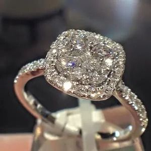 Diamond halo engagement ring in a rose gold setting on a display stand