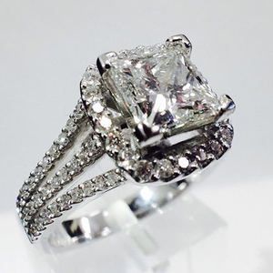 Diamond engagement ring with a large square-cut center stone and pavé band on a white stand
