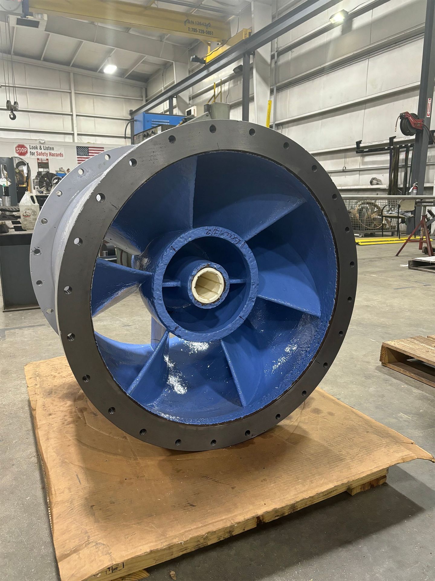 A large blue wheel is sitting on top of a wooden pallet in a factory
