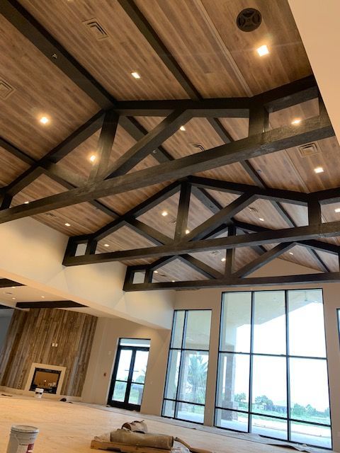 Modern lobby with wood-beamed ceiling, warm recessed lights, and large floor-to-ceiling windows.
