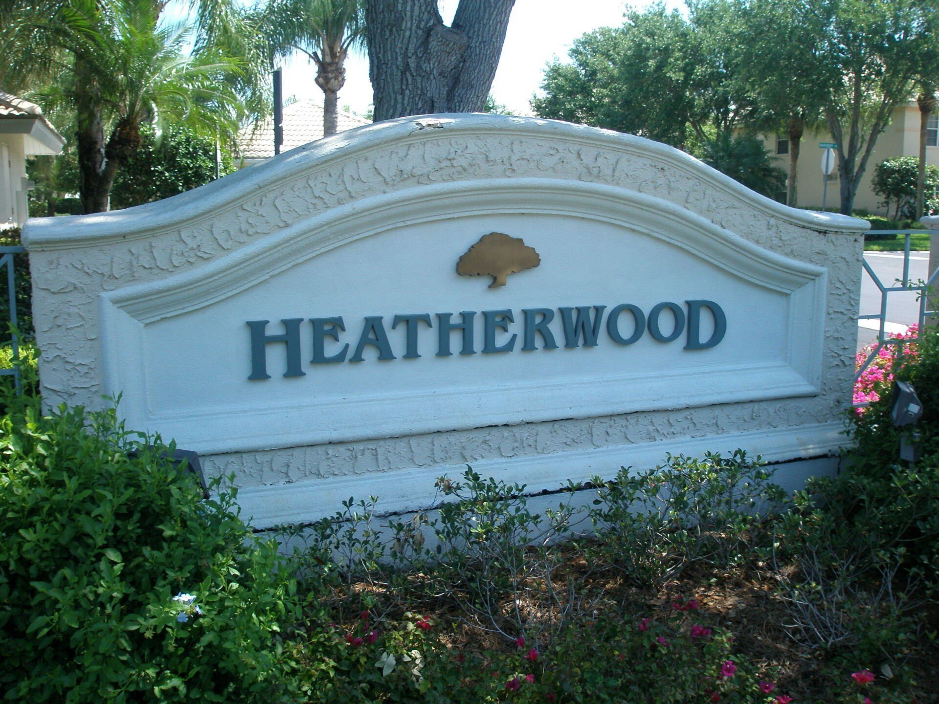 Heatherwood neighborhood entrance sign in a landscaped area with palm trees and flowers